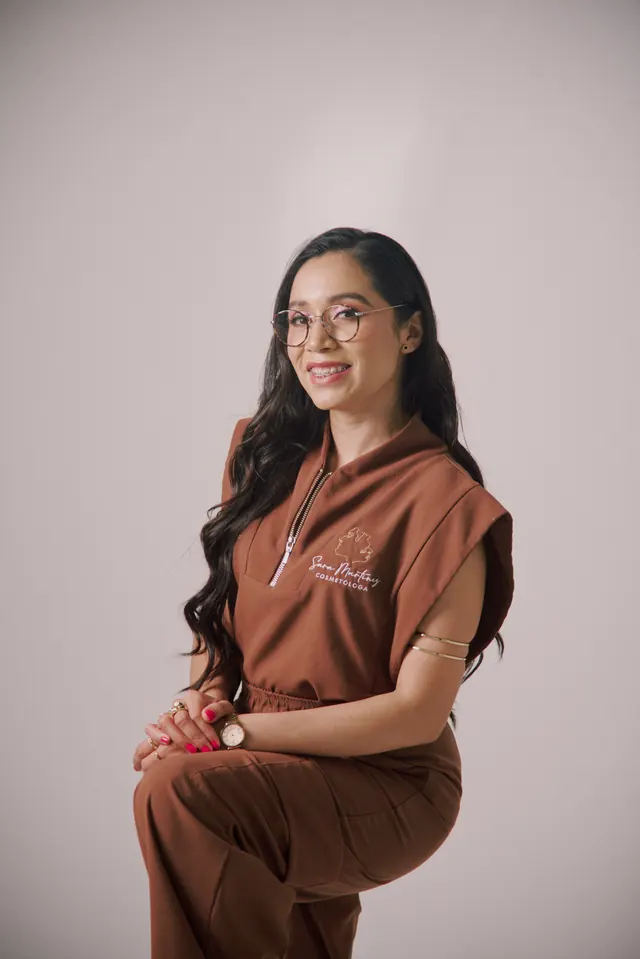 Sara Martínez sentada, sonriendo, con su uniforme café